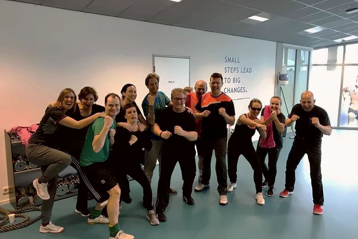 Collega's lachend in verdedigingshouding na een Krav Maga teambuildingsessie