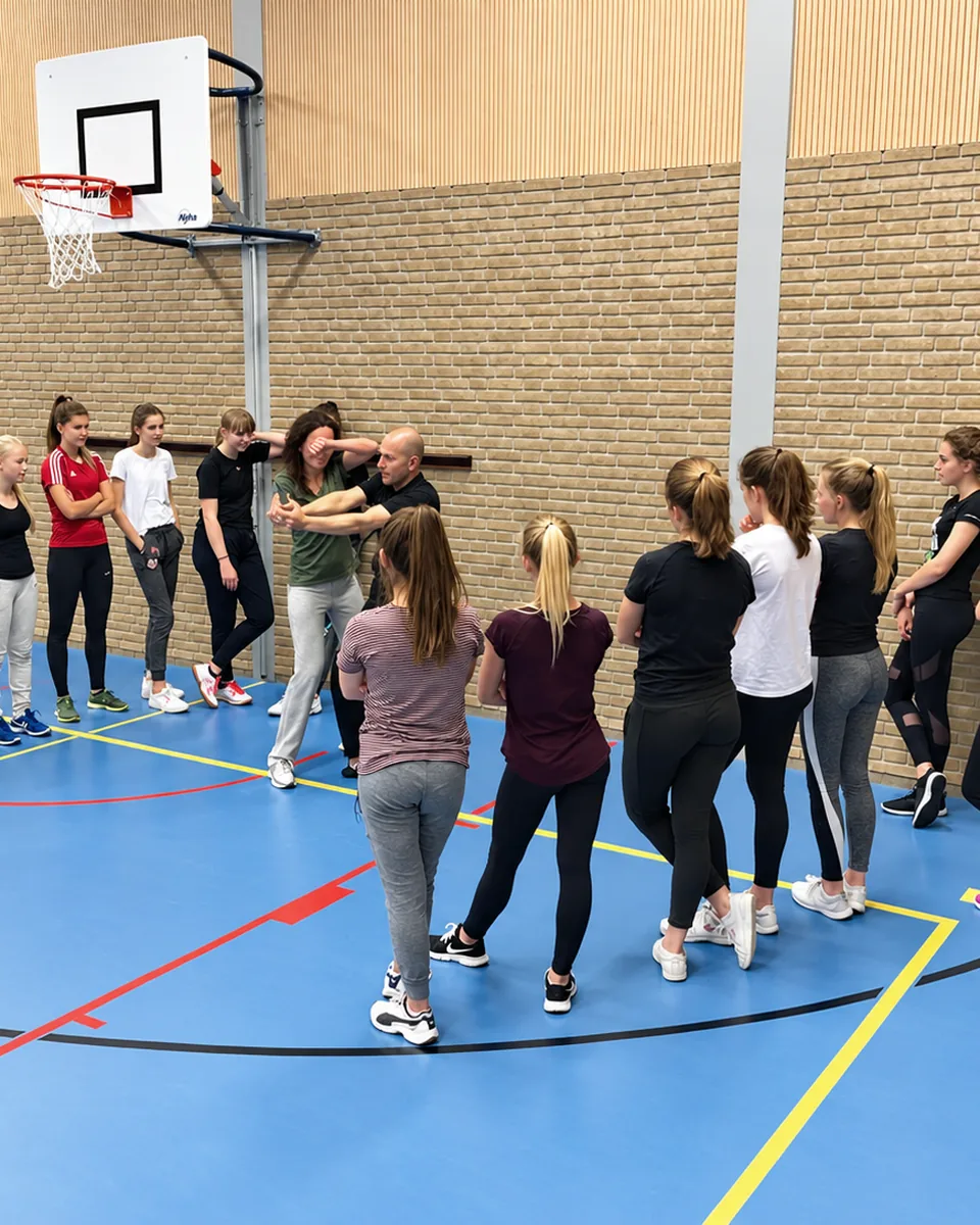 Junioren oefenen in groepjes een techniek tijdens de les in de gymzaal